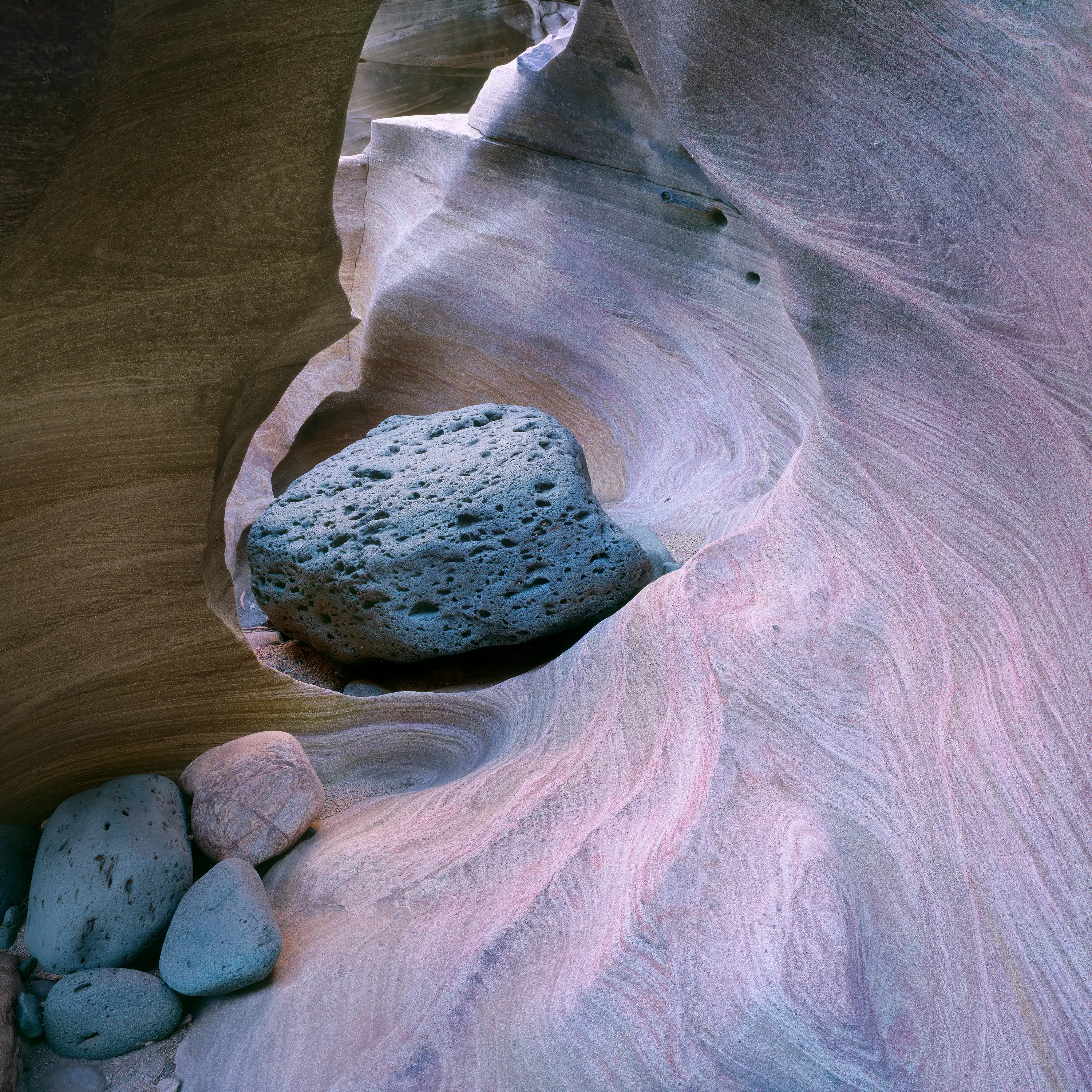 An image with pink and mauve tones of a pothole and grinder stones.