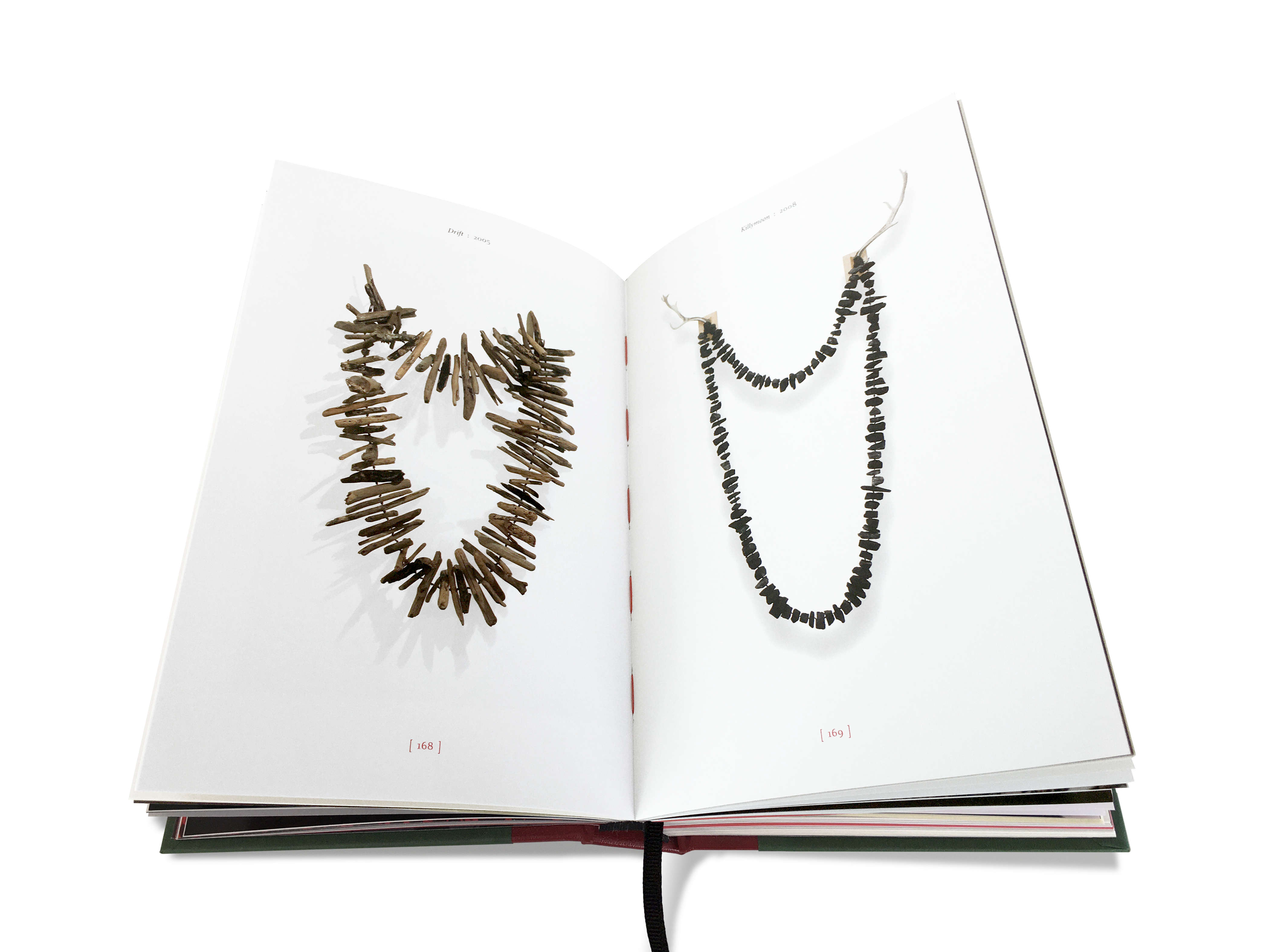 Image of a double-page spread from the TENSE PAST book (pages 168 & 169). The left-hand page features the artwork titled ‘Drift’ (2005) by Julie Gough. This large 3-D work is representative of an over-sized necklace made from driftwood. The right-hand page features the artwork titled ‘Killymoon’ (2008) by Julie Gough. This large 3-D work is representative of an over-sized necklace made from lumps of Fingal Valley coal, hanging from fallow deer antlers on wooden fixing points.