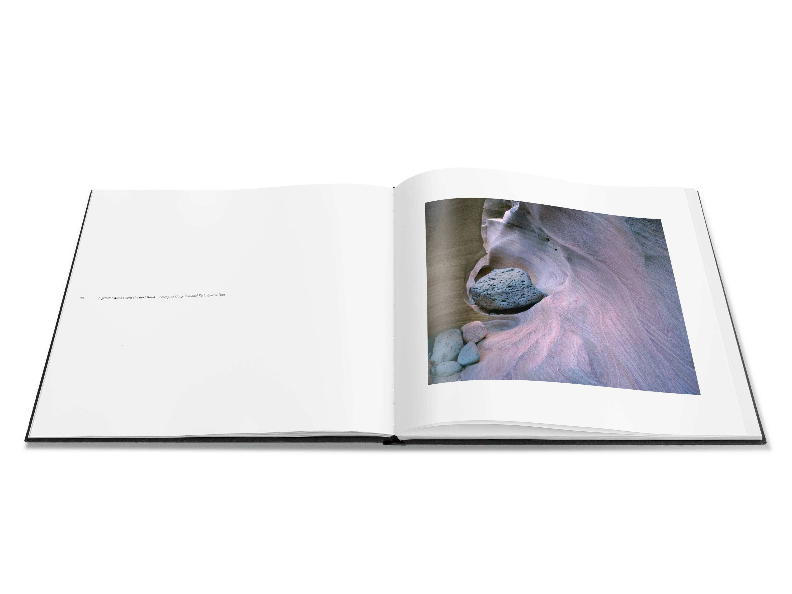 Image of a double page spread from the book featuring a photograph with pink and mauve tones of a pothole and grinder stones.