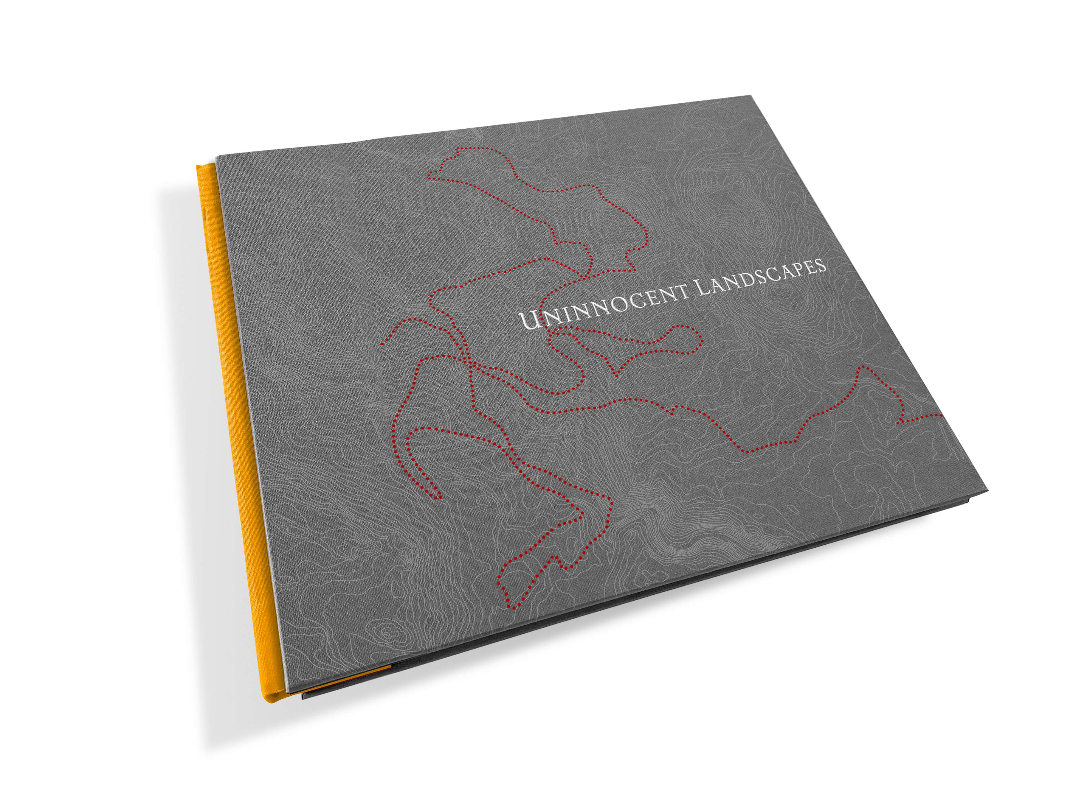An image of the cover of the Uninnocent Landscapes book, with a yellow spine. The cover is grey with silver contour lines and red foil dots that represent the route Robinson took on the Big River Mission.